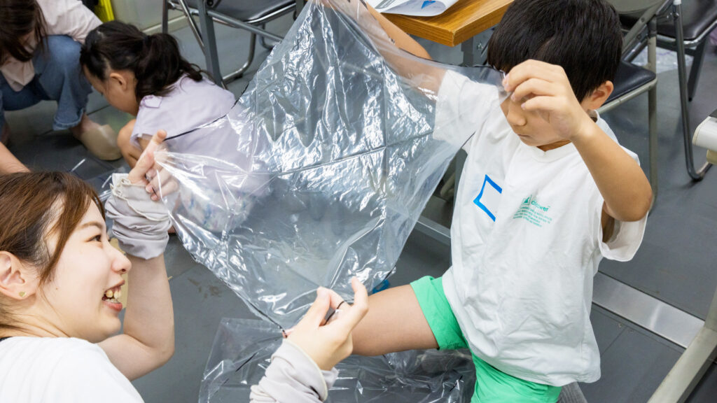 小学生がビニール袋を使ってパラシュートを工作するペットボトルロケット教室の様子