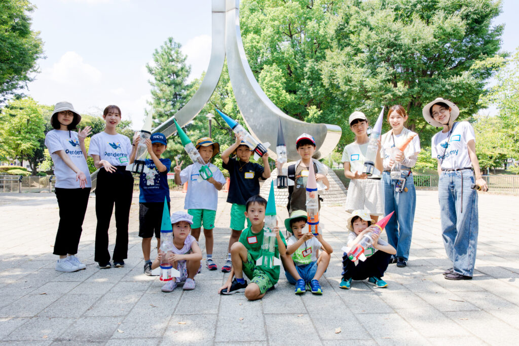 ペットボトルロケットを手に集合写真を撮る小学生とスタッフたち(STEAMイベント)