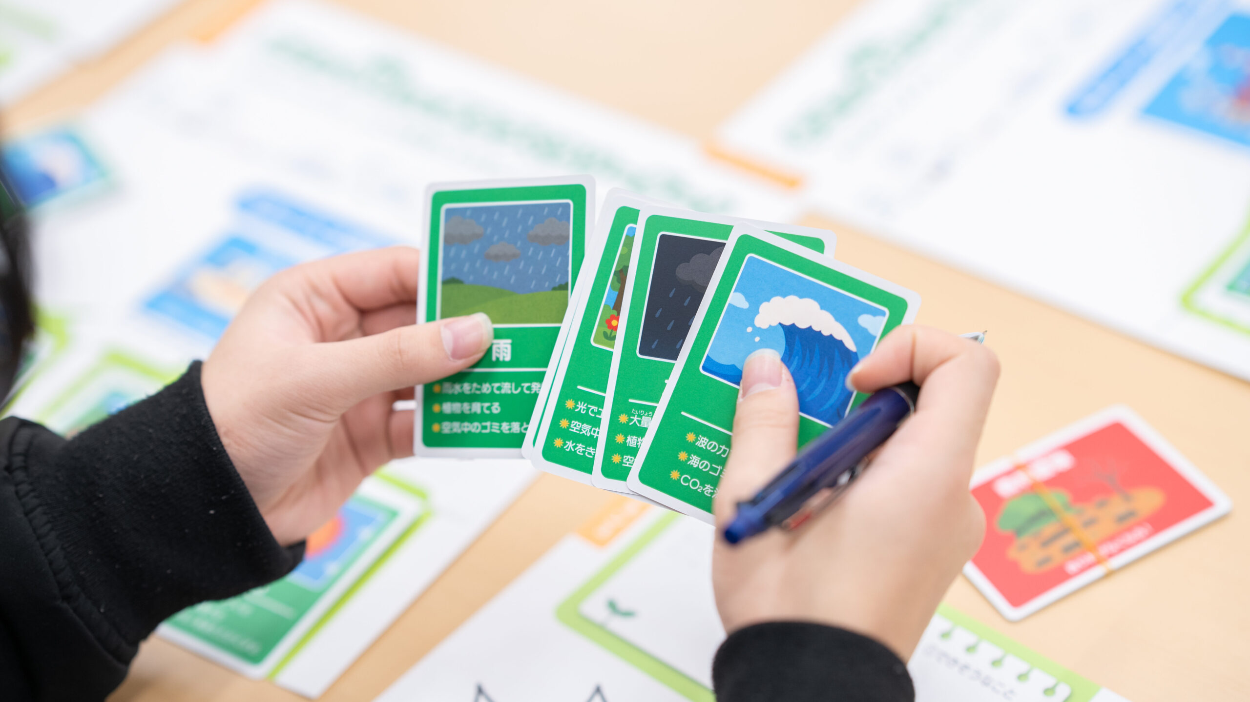 高専生がサステナブルアイテムカード（雨・植物・海など）を選び、未来の品川の環境問題解決アイデアを考えるワークショップのミッション2の様子。