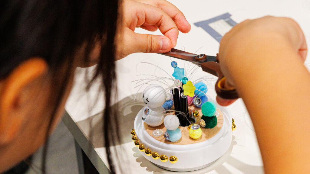 光ファイバーツリー作りの制作風景。子どもがテグス(光ファイバーの代わり)をはさみで調整し、LED作品をデコレーション(ミッテン府中)