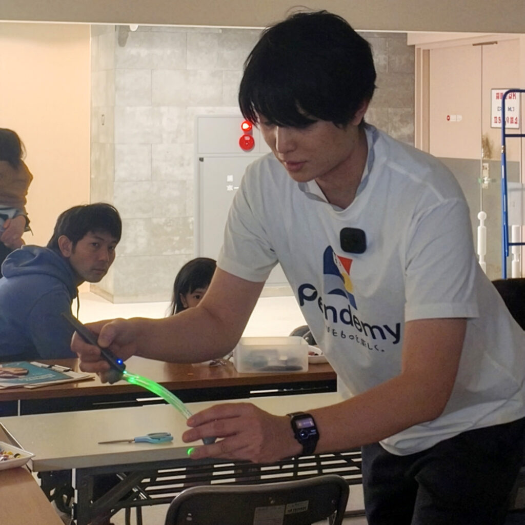 Pendemyの体験型ワークショップ(ミッテン府中)で、光ファイバーの内部反射を実演し、光の進み方を子どもたちに解説する場面