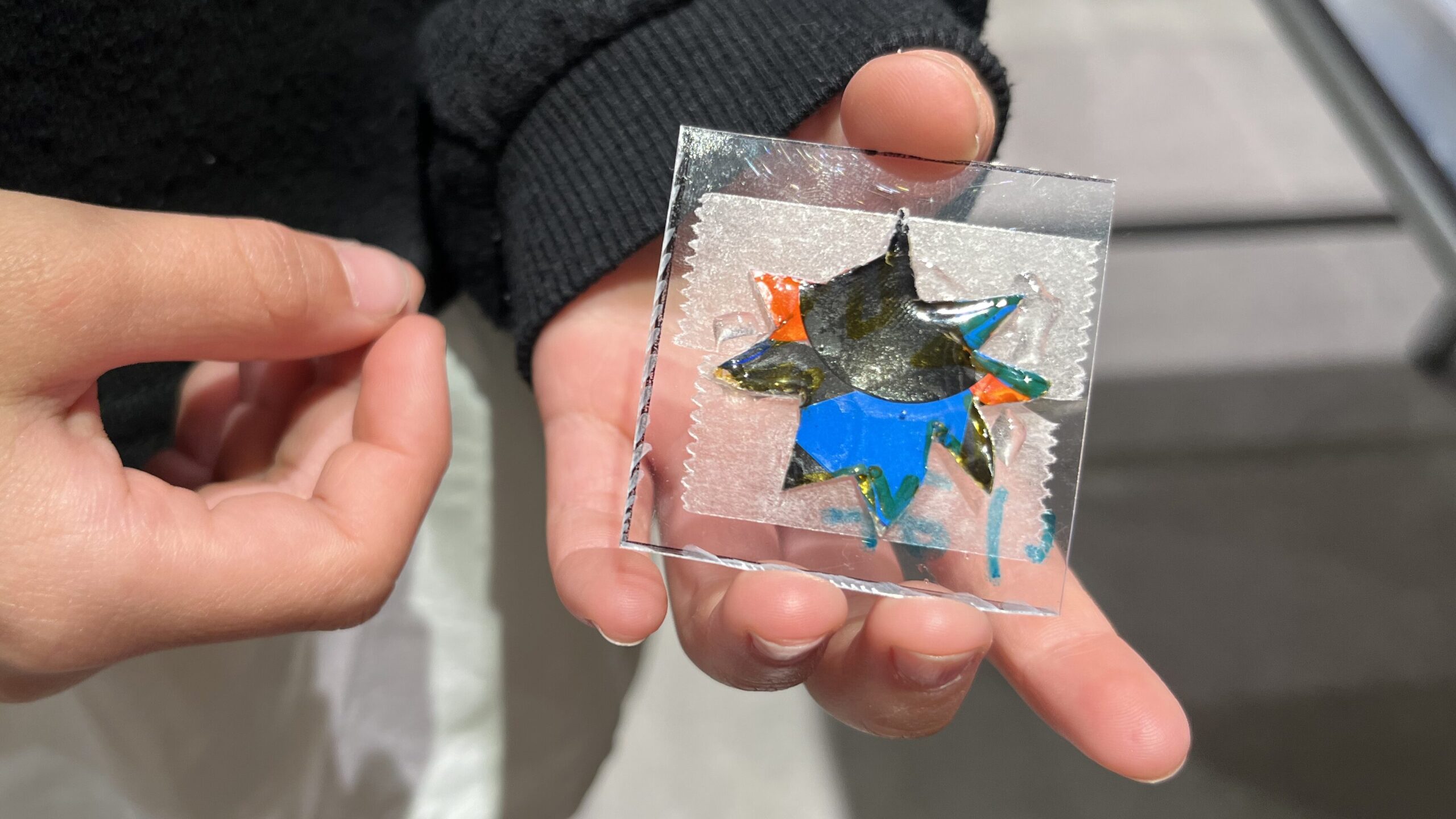 完成したボンボンドロップ風シールのアップ写真 透明の四角いシートの中に 星形に切ったカラフルな素材が重なって見える