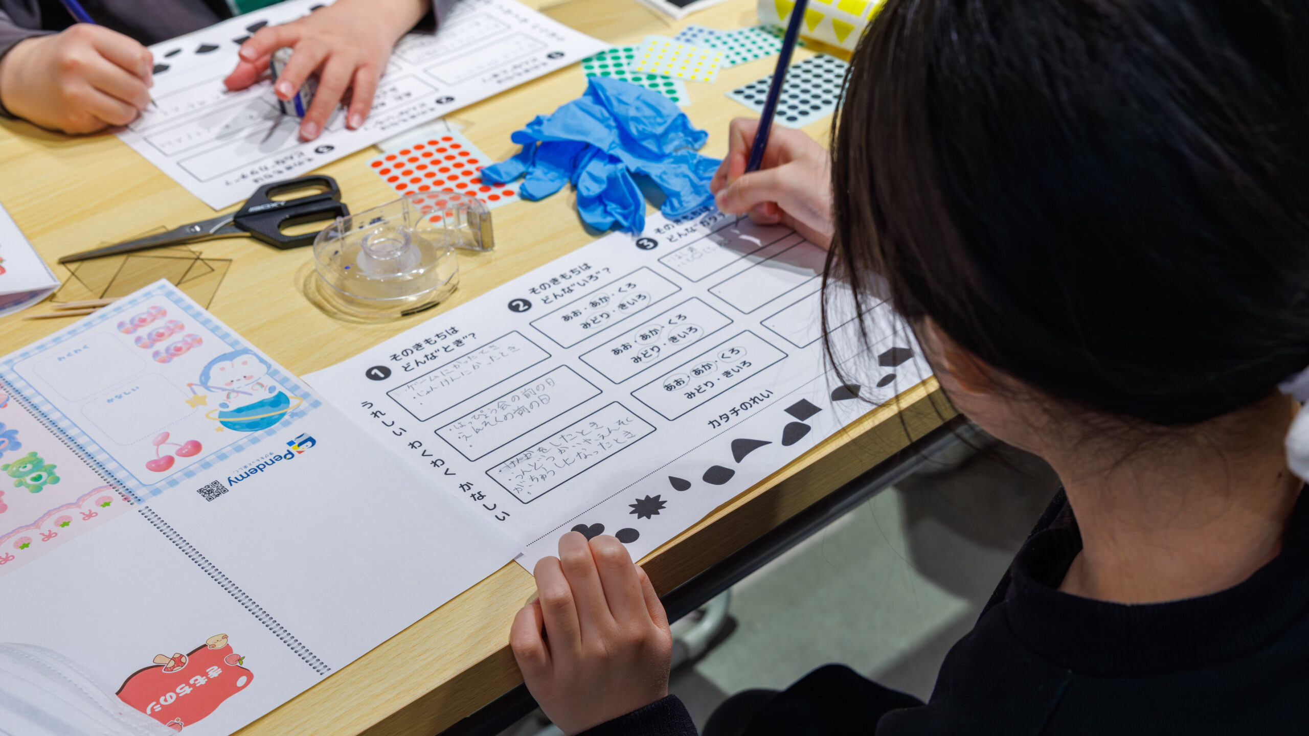 ワークシートに気持ちの色とカタチを書き込む小学生の手元