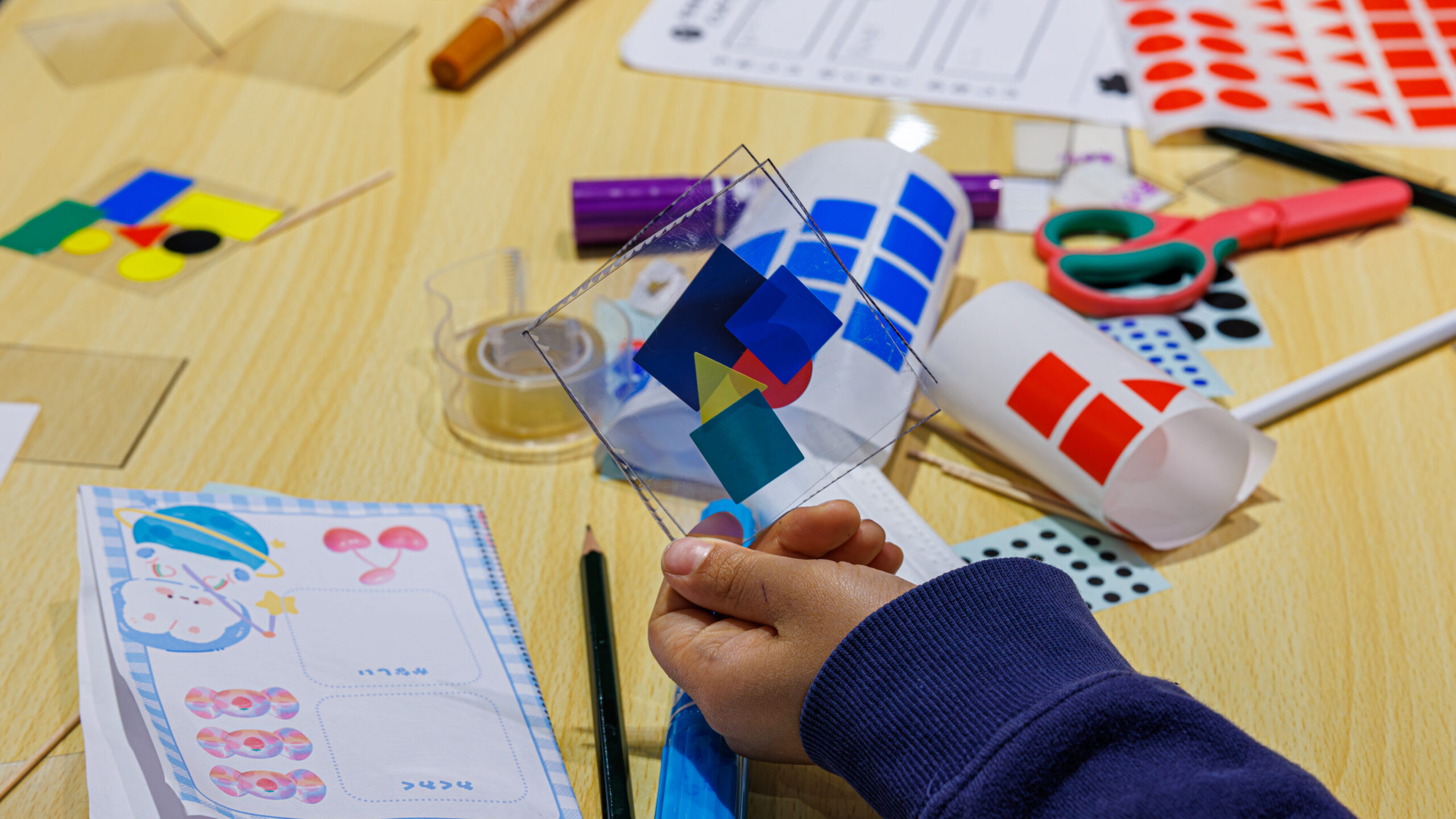 3色のシール素材を台紙に貼ってデザインしている様子