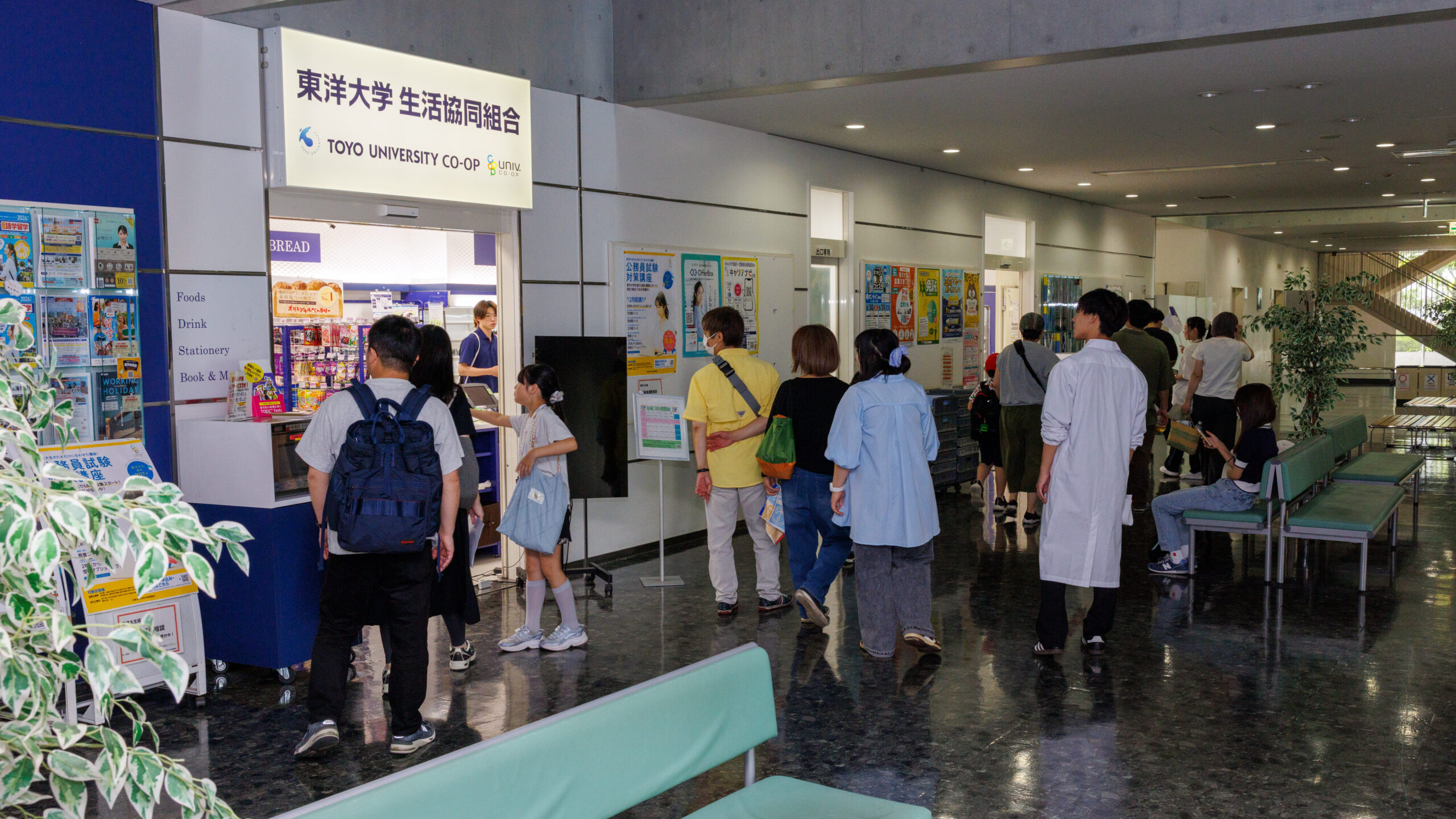 東洋大学生活協同組合の売店前を通り学食へ向かうオープンキャンパス参加の親子