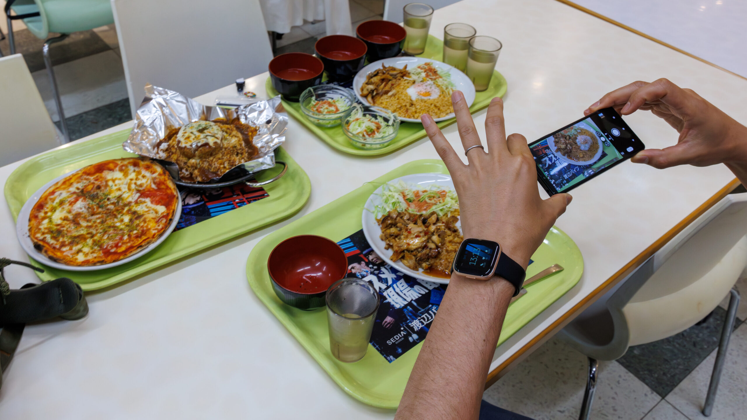 東洋大学の学食で並んだピザやカツ丼などのメニューをスマホで撮影する様子
