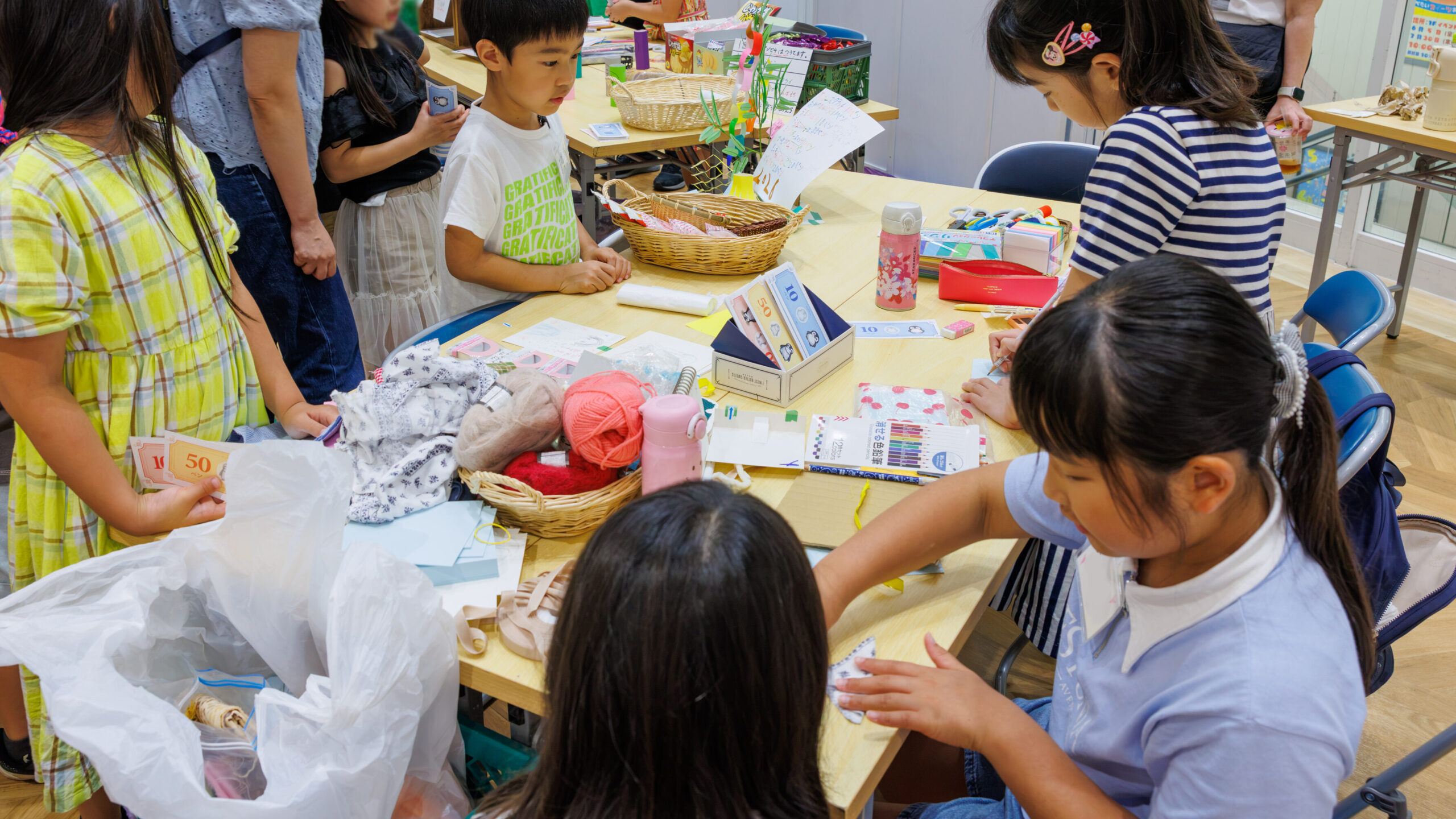子ども店長プロジェクトで手作り雑貨のお店に集まり手作りのお金で買い物をする小学生たち