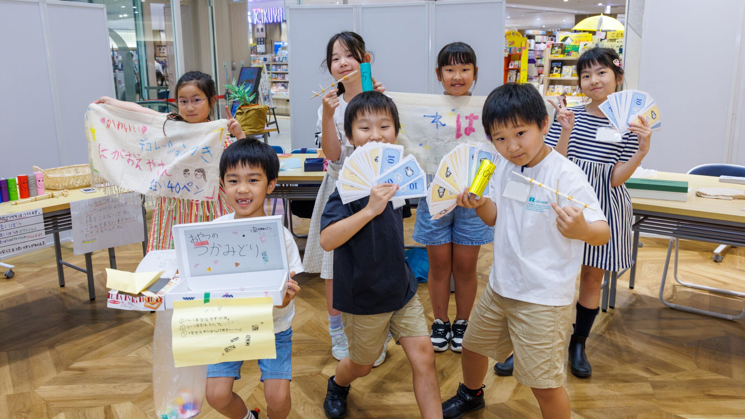子ども店長プロジェクトで各お店の店長たちが手作りのお金を手に集合した記念写真