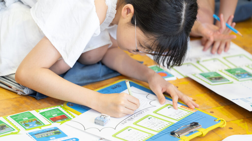 ワークシートの吹き出し欄に、パワーアップした施設のイメージ図を鉛筆で描く小学生の手元