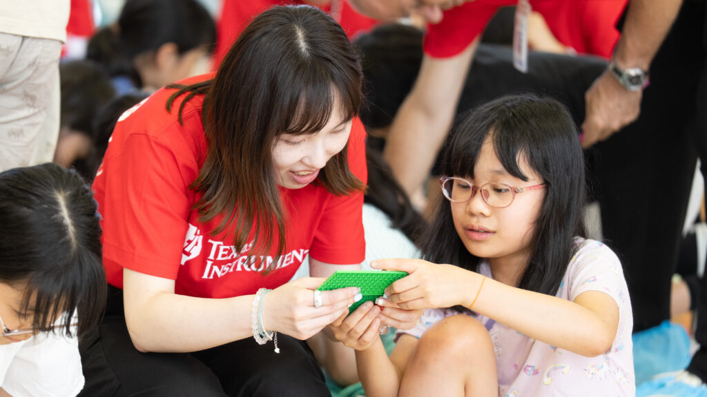 レゴブロックを手にした小学生とTI社員が向き合って作業する様子
